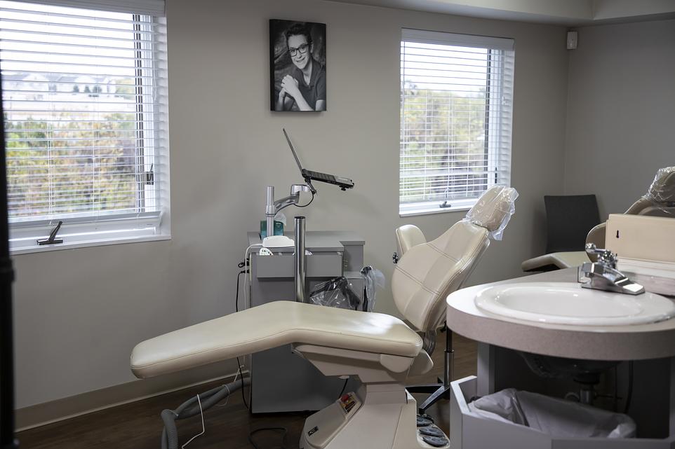 Modern dental operatory with cream-colored chair, overhead light, and round sink in professional orthodontic office.