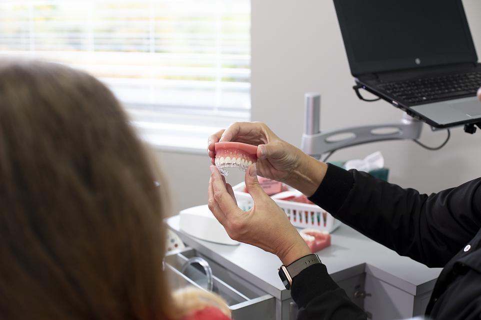 Orthodontist demonstrates dental model to patient during consultation in modern clinic office.