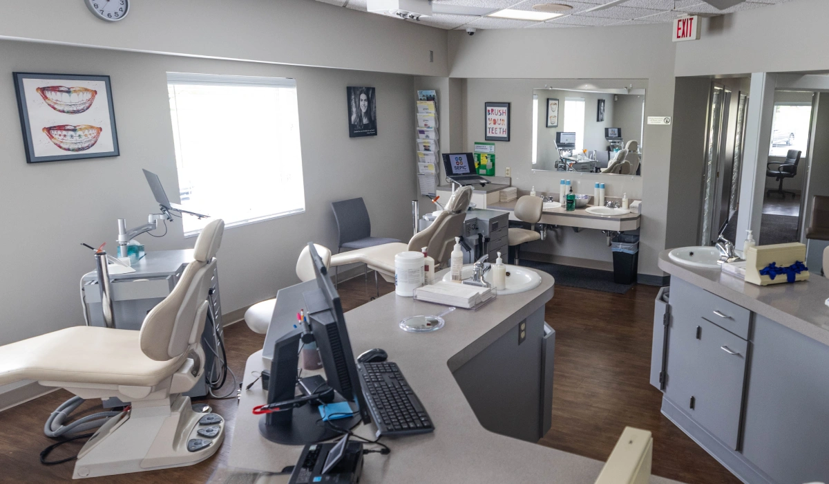 Modern orthodontic office treatment room with dental chair, equipment, and sterilization station.