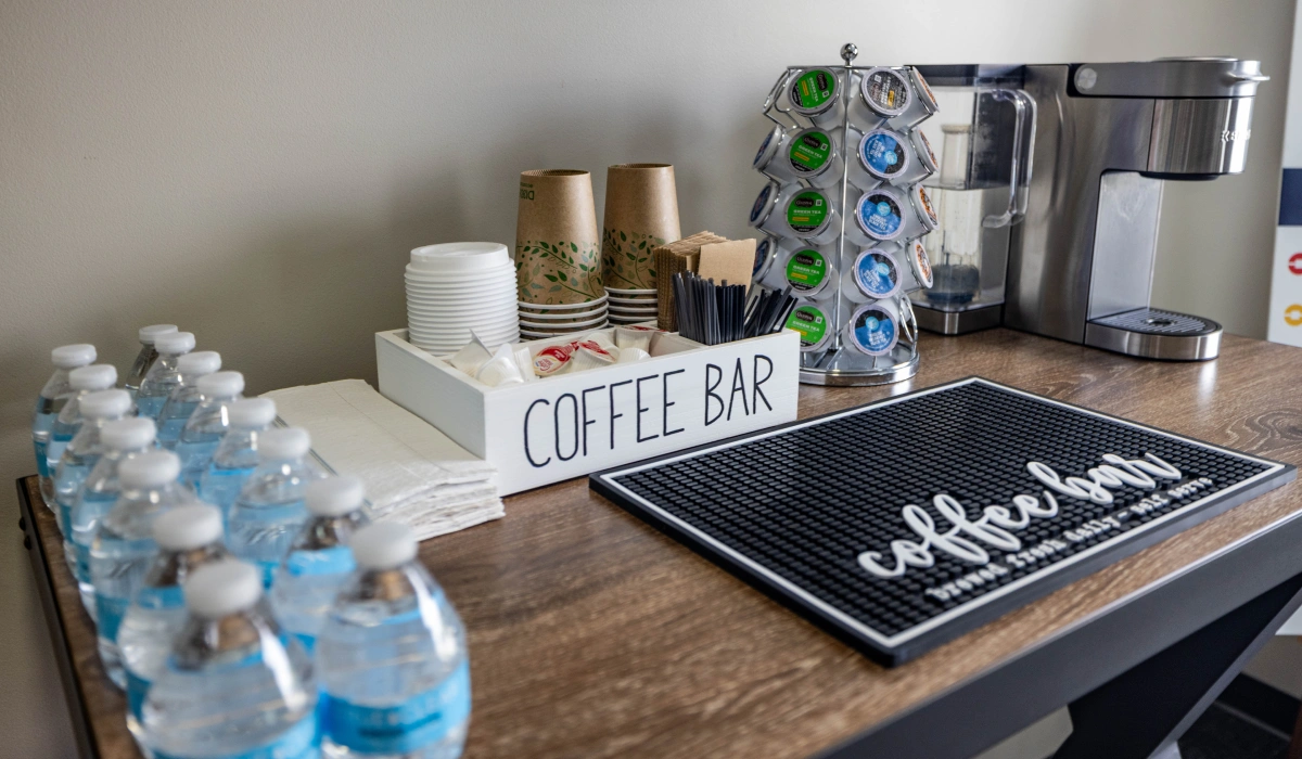 Orthodontics office break room with coffee bar, water bottles, and chess board on wooden counter.