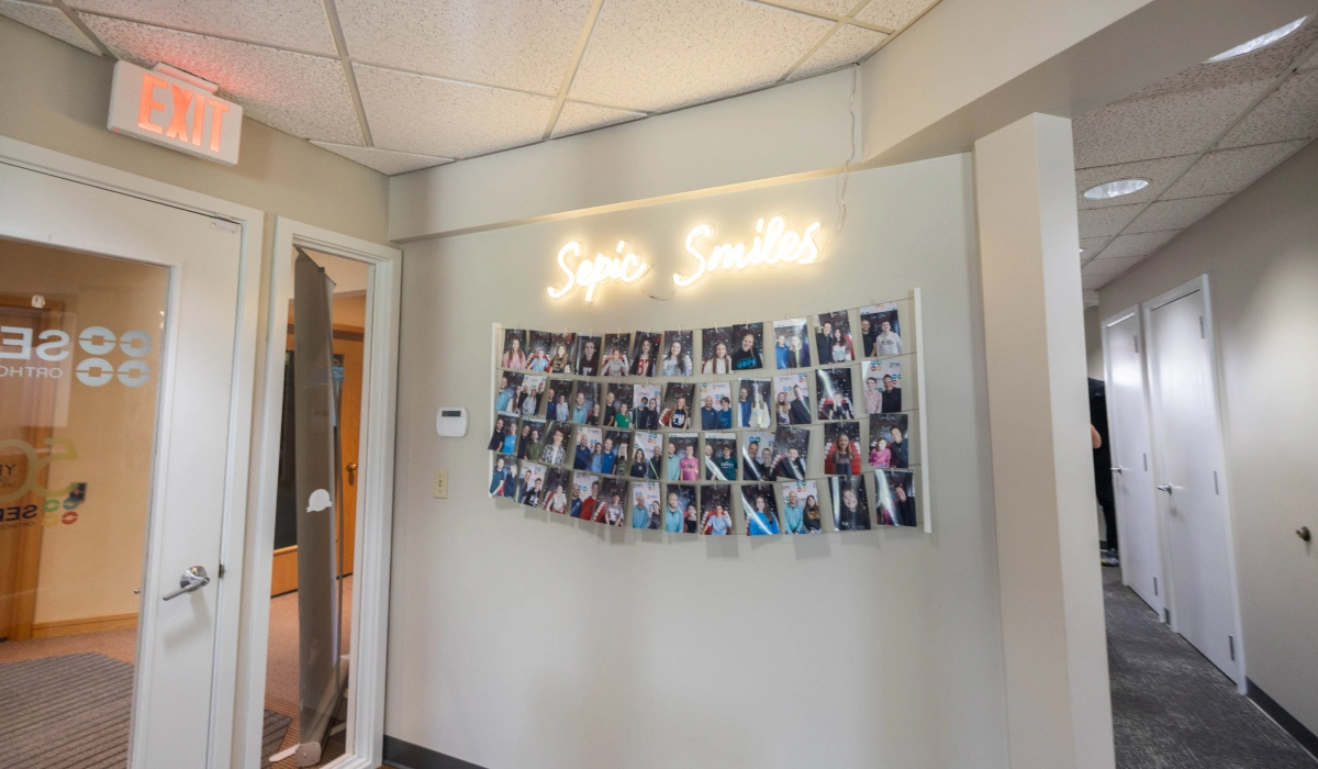 Orthodontics office hallway with collage of patient photos displayed on wall near entrance