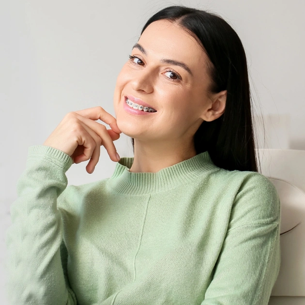Young woman in light green sweater smiling thoughtfully against white background.
